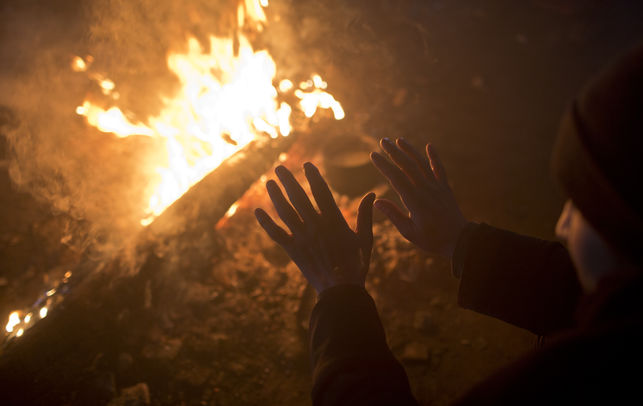 Un home s'escalfa les mans al foc dins d'un magatzem abandonat a Belgrad, Sèrbia, el 5 de gener del 2017 / Metges Sense Fronteres